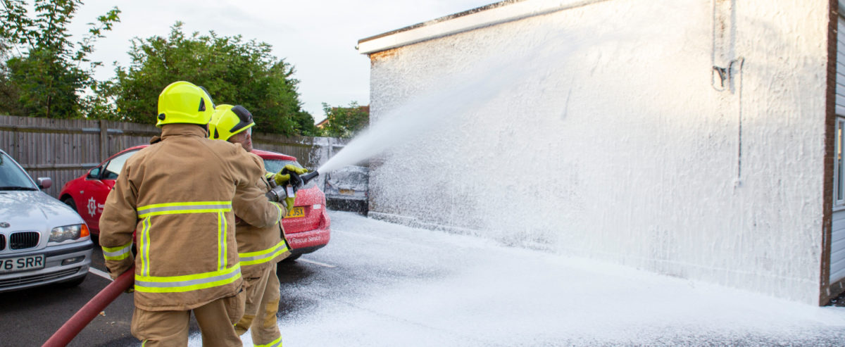 Kent Fire & Rescue firemen spraying building with foam